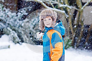 Happy kid boy having fun with snow in winter