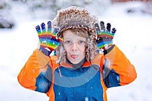 Happy kid boy having fun with snow in winter