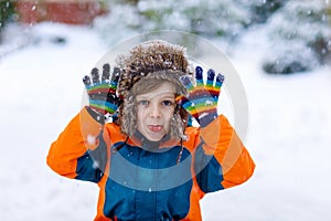 Happy kid boy having fun with snow in winter