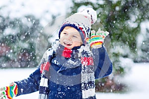 Happy kid boy having fun with snow in winter