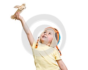 Happy kid boy in helmet pilot plays with wooden toy airplane. Isolated on white background.