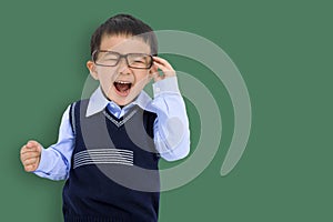 Happy Kid boy holding glasses and having fun stand before chalkboard