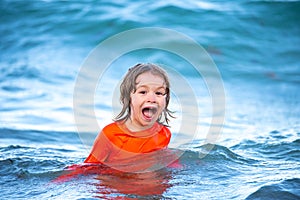 Happy kid boy playing and having fun on the beach on blue sea in summer. Blue ocean with wawes. Child boy swimming in photo