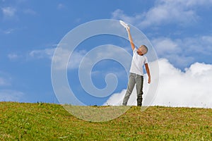 Happy kid boy playing with toy airplane against blue sky background