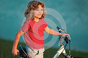 Happy kid boy riding bike in summer park. Bike dream. Dreamy kids face. Daydreamer child portrait close up. Dreams and photo