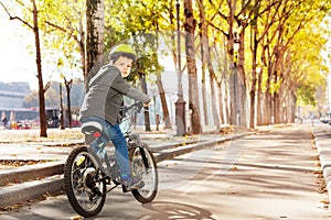 Happy kid boy riding his bike on cycle lane