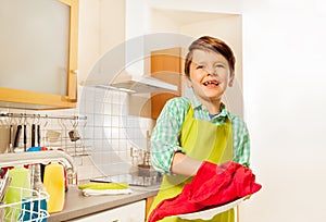 Happy kid boy wiping dry plate with red dish towel