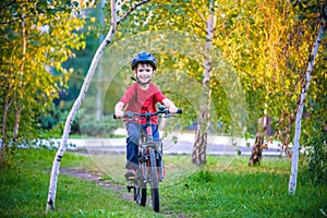 Happy kid boy of 6 years having fun in autumn forest with a bicycle on beautiful fall day. Active child making sports. Safety, sp