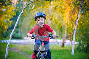 Happy kid boy of 6 years having fun in autumn forest with a bicycle on beautiful fall day. Active child making sports. Safety, sp