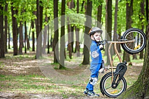 Happy kid boy of 4 years having fun in autumn or summer forest with a bicycle