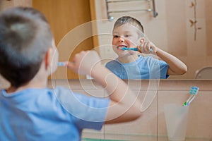 Happy kid or child brushing teeth in bathroom.