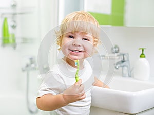 Happy kid or child brushing teeth in bathroom