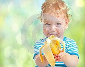 Happy kid eating banana fruit. healthy food eating concept.