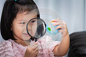 Happy kid exploring globe map with magnifying glass. Child aged 4-5 years old
