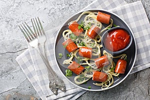 Happy kid food for Halloween party spaghetti with sausages and ketchup close-up in a plate. Horizontal top view