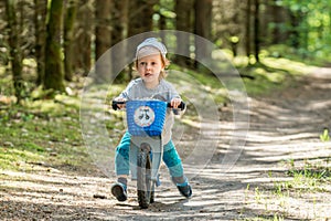 happy kid in forest with balance bike riding fast
