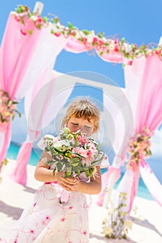 Happy kid girl in beautiful dress on tropical wedding setu