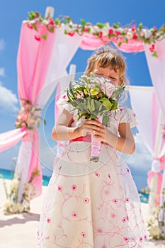 Happy kid girl in beautiful dress on tropical wedding setu