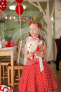 Happy kid girl celebrating birthday party with bouquet of flowers in cafe