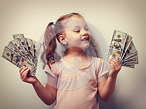 Happy kid girl holding cash dollars and looking with smile. Vint