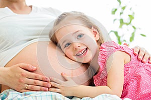 Happy kid girl hugging pregnant mother