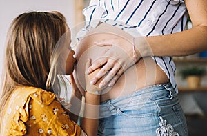 Happy kid girl hugging pregnant mother`s belly