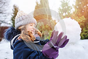 Happy kid girl making snow man on Christmas vacations on backyard