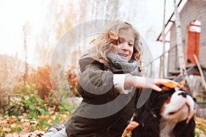 happy kid girl playing with her cavalier king charles spaniel dog in autumn