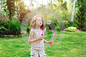 Happy kid girl playing with soap bubbles