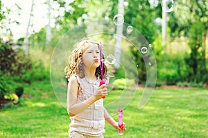 Happy kid girl playing with soap bubbles