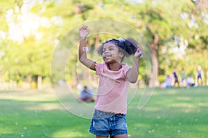 Happy kid girl playing with soap bubbles. Active child playing outdoor in the park