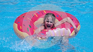 Happy kid girl playing in swimming pool with inflatable lap. Summer family vacations