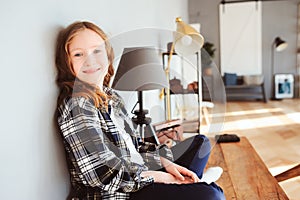 Happy kid girl sitting on table at home and wring. Learning lessons, successfull education