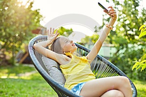 Happy kid girl take selfie on mobile phone in the park outdoor