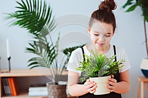 Happy kid girl taking care of houseplants at home, dressed in stylish black and white outfit