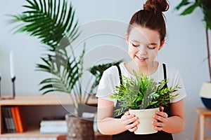 happy kid girl taking care of houseplants at home, dressed in stylish black and white outfit