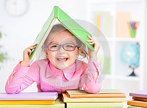 Happy kid in glasses under roof made from book