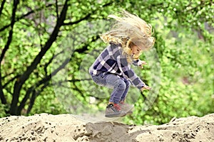 Happy kid having fun. Child bounce on sand in spring or summer park