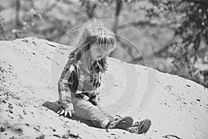 Happy kid having fun. Toddler slide from pile of sand on idyllic sunny day