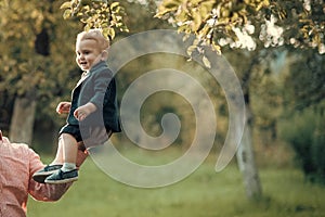 Happy kid having fun. Cute toddler smile in suit, shirts, sneakers under tree, fashion