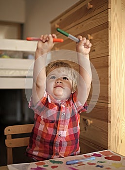 Happy kid having fun. Kid or blonde happy boy paint with felt pen.