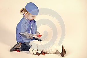 Happy kid having fun. small boy in doctor uniform playing vet with toy animal