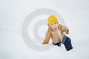 Happy kid having fun on winter field with snow. Winter Christmas emotion. Happy laughing toddler boy playing in a snowy