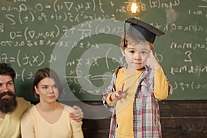 Happy kid having fun. Wunderkind concept. Smart child, wunderkind in graduate cap pointing at his head. Boy presenting