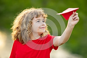 Happy kid hold paper planes. Toy airplane in children hands outdoor. Happy boy leaning and throwing yellow paper