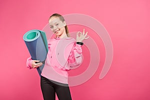 happy kid holding fitness mat and showing ok sign, isolated