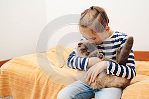 Happy kid hugging his cat. Boy relaxing on the bed with pet. Childhood, true friendship and home pet