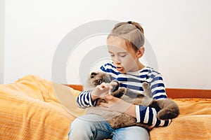 Happy kid hugging his cat. Boy relaxing on the bed with pet. Childhood, true friendship and home pet