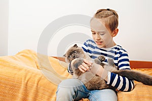 Happy kid hugging his cat. Boy relaxing on the bed with pet. Childhood, true friendship and home pet