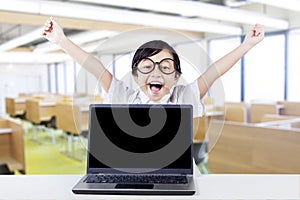Happy kid with laptop raise hands in class